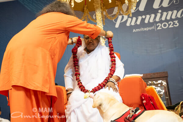 Swami legt Amma eine Blumengirlande um